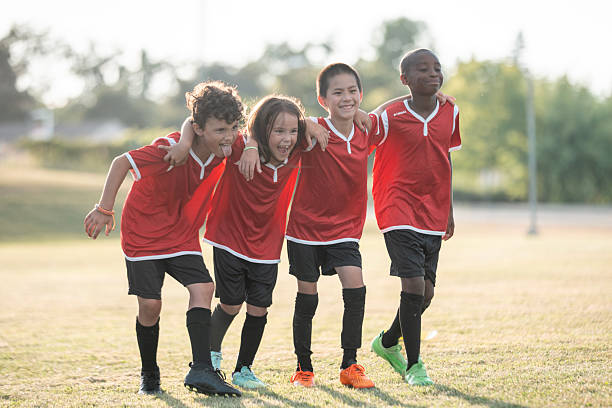 Young players arm in arm, smiling after training